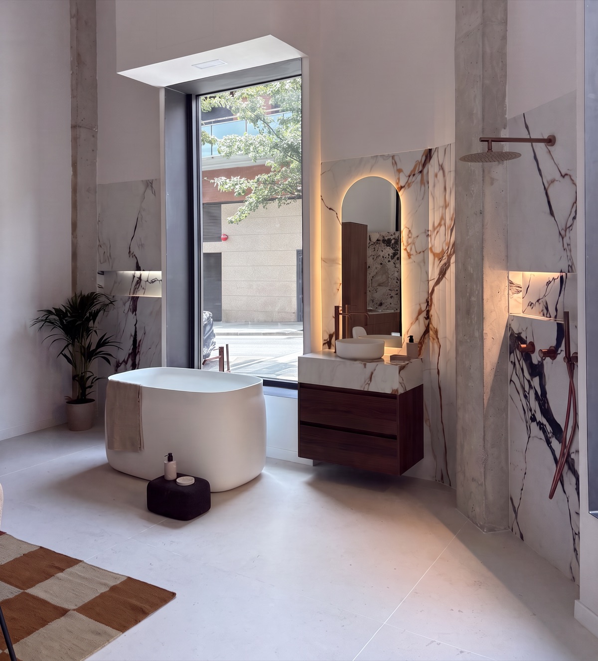 Baño del showroom con bañera exenta y mármol a libro abierto